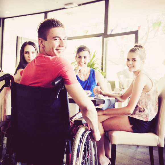 young disabled man having fun with his friends at cafe