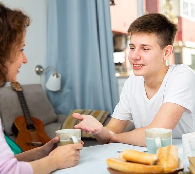 happy teenager having friendly chat with his mom at home